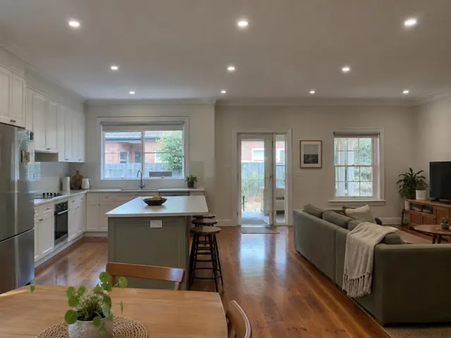 Modern open-plan kitchen and living room with recessed LED downlights, timber floor and white walls in Wallsend